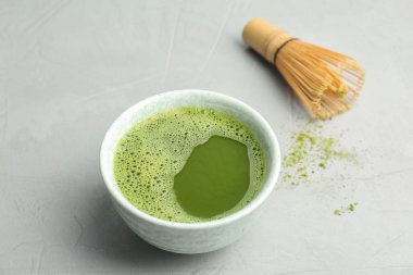 Taze matcha çay ve gri arka plan üzerinde chasen kase