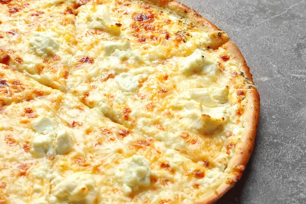 Gri zemin üzerine lezzetli sıcak peynirli pizza