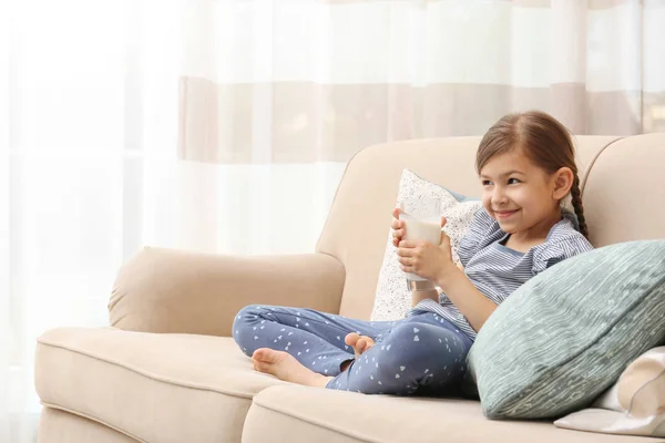 Χαριτωμένο Μικρό Κορίτσι Ποτήρι Γάλα Στον Καναπέ Στο Σπίτι — Φωτογραφία Αρχείου
