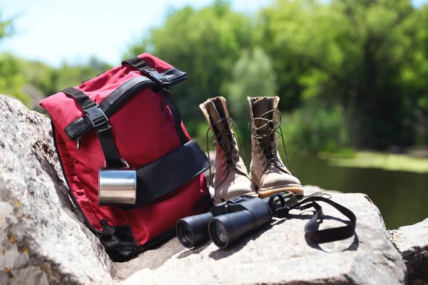 Traveling gear on rock near river. Summer camp