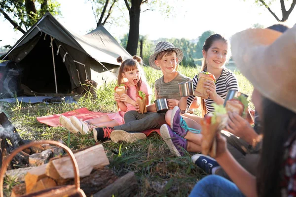 Küçük çocuklar şenlik ateşi ve çadır sandviç yeme. Yaz Kampı