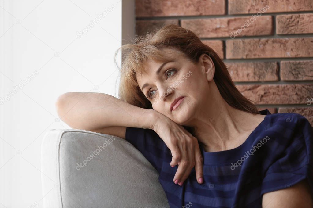 Senior woman suffering from depression in armchair