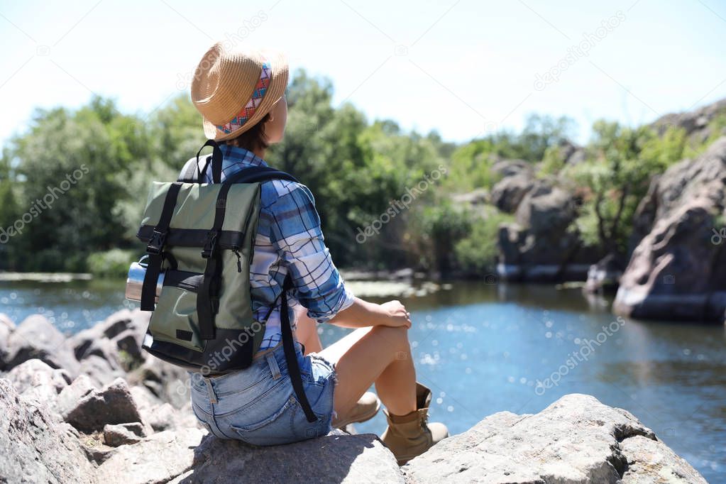 Young woman on rock near river. Summer camp