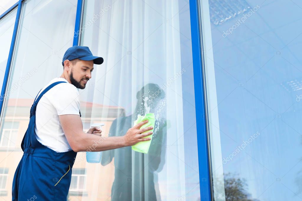 Male worker washing window glass from outside