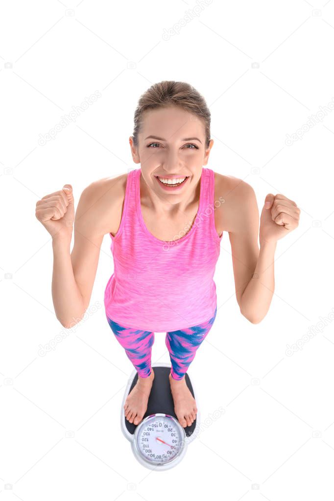Happy young woman measuring her weight using scales on white background. Weight loss motivation