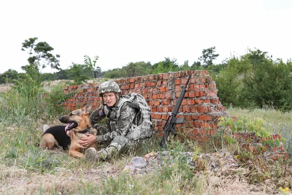 レンガの壁の近くにドイツの羊飼いの犬と軍の制服の男 — ストック写真