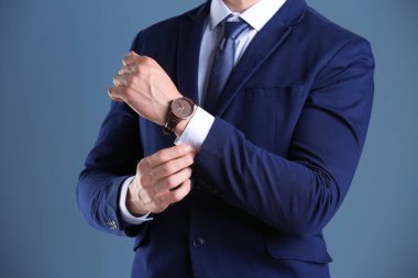 Renk arka plan üzerinde kol saati ile iş adamı. Zaman kavramı