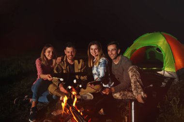 Arkadaşlar gece şenlik ateşi üzerinde Marshmallows kızartma. Kamp sezon