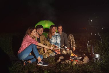 Arkadaşlar gece şenlik ateşi üzerinde Marshmallows kızartma. Kamp sezon