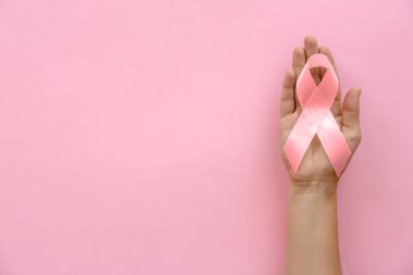 Meme kanseri bilinçlendirme şerit sembolik renk arka planda, üstten görünüm tutan kadın. Jinekolojik bakım