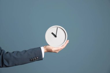 Saat renk arka plan üzerinde tutan genç iş kadını. Zaman yönetimi
