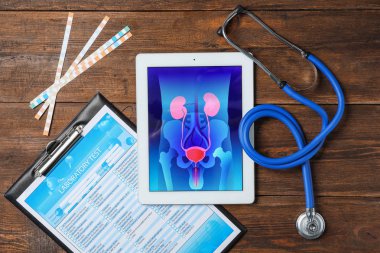 Ahşap arka plan üzerinde tablet, stetoskop ve test formu ile düz yatıyordu kompozisyon. Üroloji kavramı