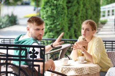 Genç çift Cafe, açık havada otururken savunarak. İlişki sorunları