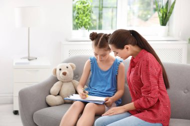 Ofiste küçük bir çocukla çalışan genç bir psikolog.
