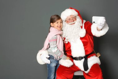 Otantik Noel Baba alarak selfie gri arka plan üzerinde küçük kızla