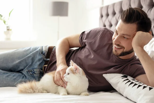 自宅のベッドの上のかわいい猫と若い男 — ストック写真