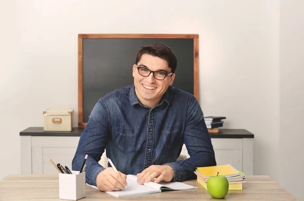 stock image Portrait of male teacher sitting at table in classroom