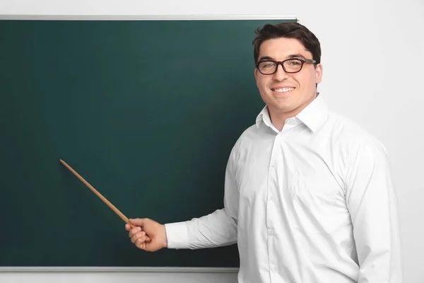 教室の黒板の近くにポインターを持つ男性教師の肖像 — ストック写真