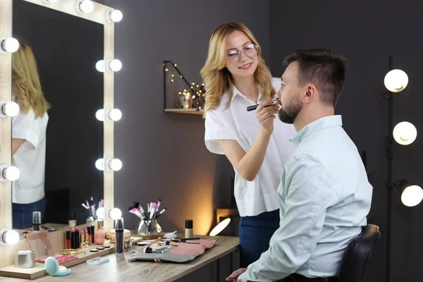 Professional makeup artist working with client in dressing room