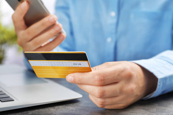 Young woman with credit card using smartphone at table