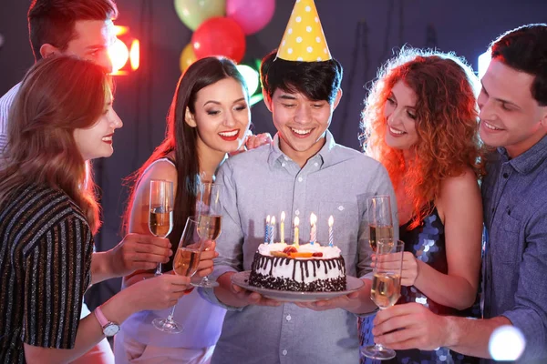 Young people celebrating birthday with cake in nightclub