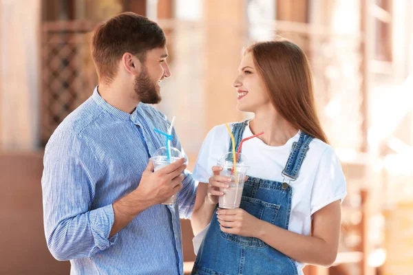 年轻夫妇与杯美味的牛奶摇户外 — 图库照片
