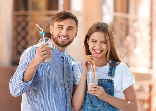 年轻夫妇与杯美味的牛奶摇户外 — 图库照片