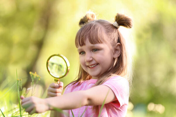 Little girl exploring plant outdoors. Summer camp