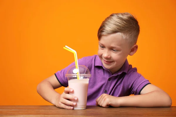Liten Pojke Med Kopp Milkshake Vid Bord Färgbakgrund — Stockfoto