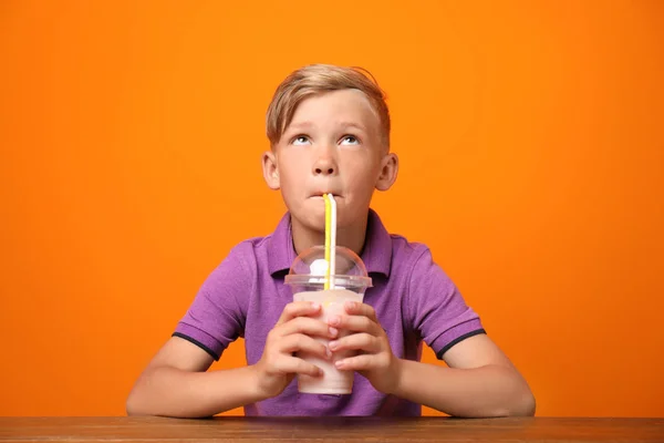 Liten Pojke Med Kopp Milkshake Vid Bord Färgbakgrund — Stockfoto