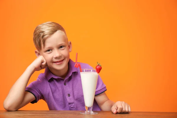 Liten Pojke Med Glas Milkshake Vid Bord Färgbakgrund — Stockfoto