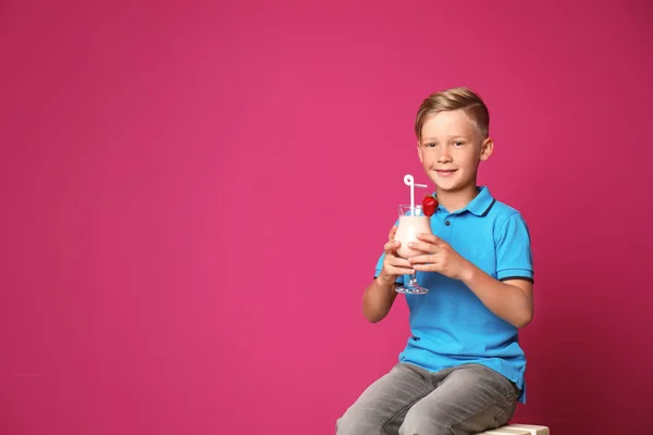 小男孩与玻璃牛奶震动在凳子反对颜色背景 — 图库照片