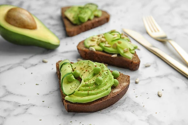 Mermer masa üzerine dilimlenmiş avokado ile net çavdar ekmeği