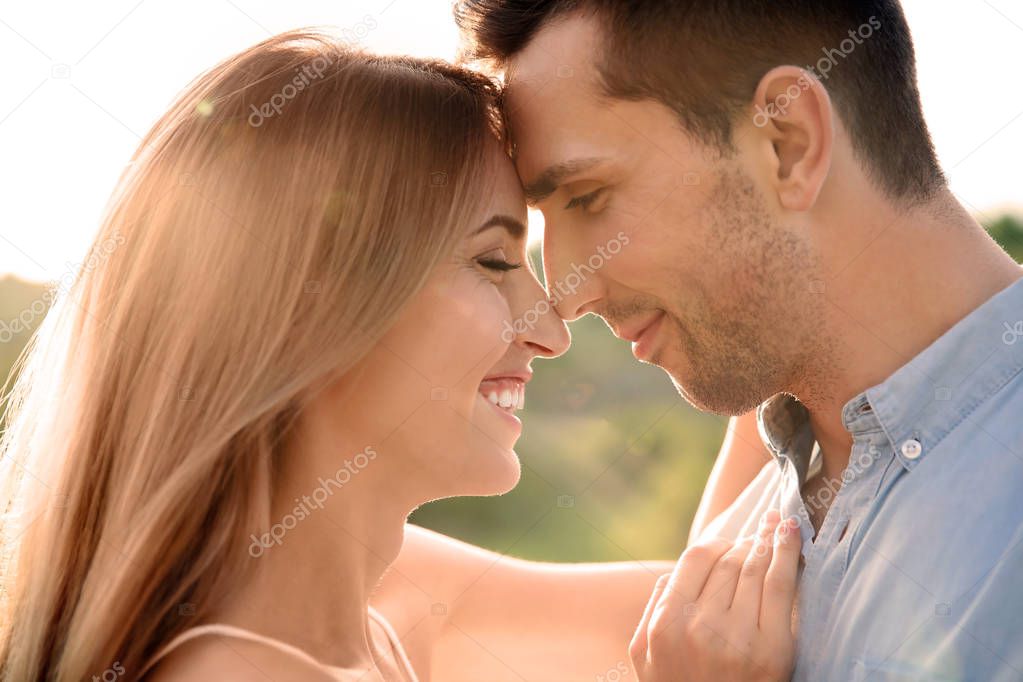 Cute young couple in love posing outdoors on sunny day