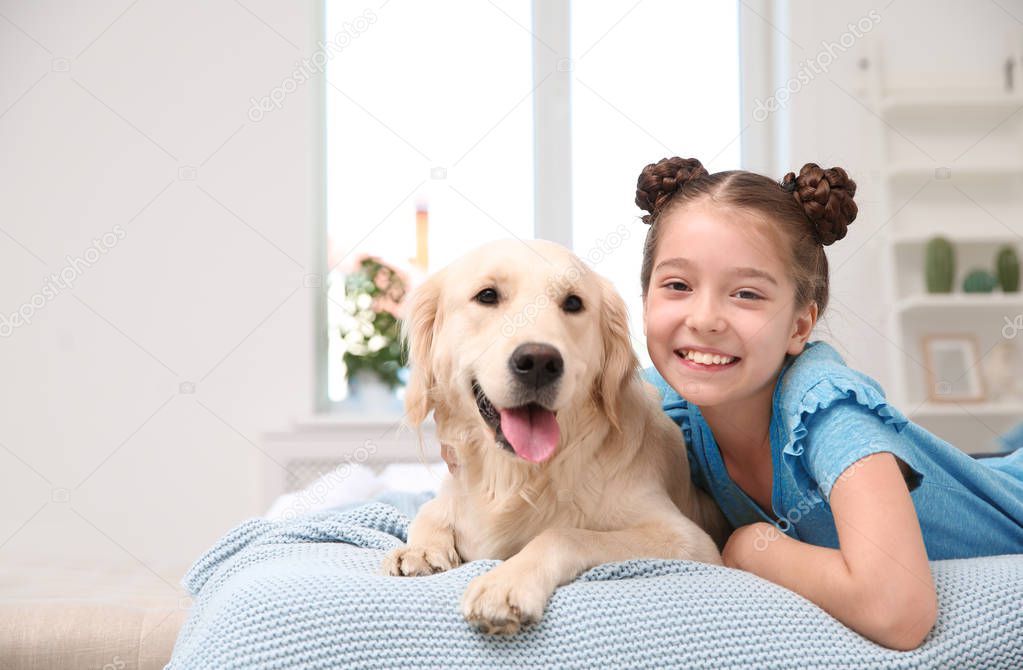 Cute little child with her pet on bed at home