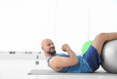 Egzersiz fitness topu içinde jimnastik salonu ile yapan kilolu erkek