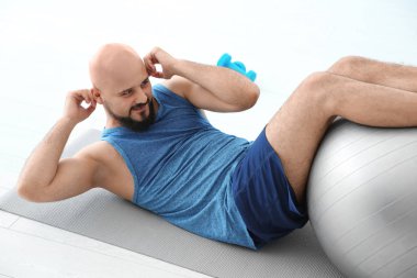 Egzersiz fitness topu içinde jimnastik salonu ile yapan kilolu erkek
