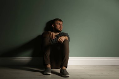 Katta karanlıkta oturan depresif genç adam