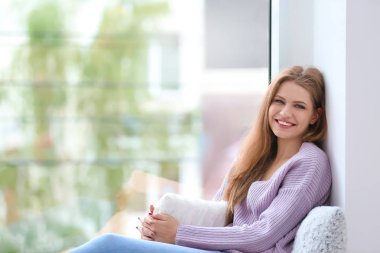 Pencere evde oturan genç mutlu kadın