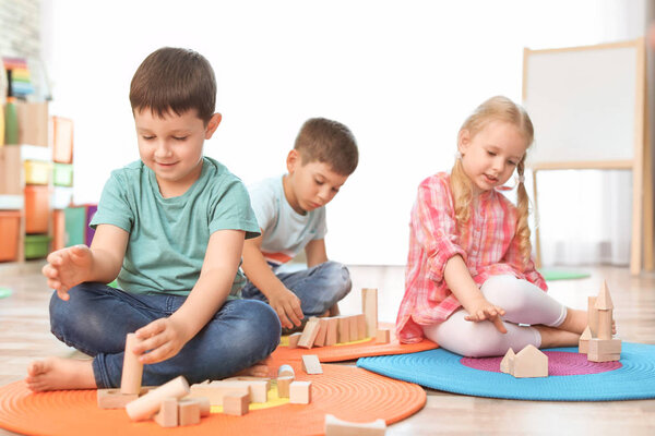 Cute little children playing with wooden blocks indoors