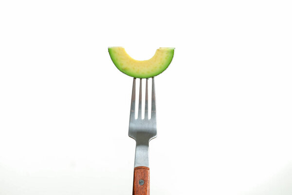 Fork with slice of avocado on white background