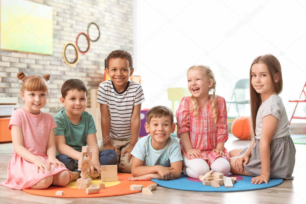 Cute little children playing with wooden blocks indoors