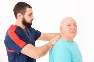 Klinikte kıdemli bir hastayla çalışan genç bir fizyoterapist.