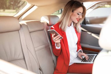Smartphone ve araba içinde laptop ile genç iş kadını
