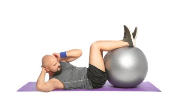Kilolu adam beyaz arka plan üzerinde fitness topu ile egzersiz yaparak