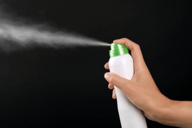Genç kadın deodorant siyah arka plan üzerine püskürtme