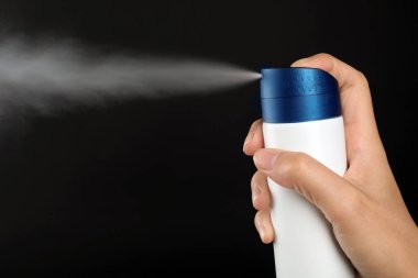 Genç kadın deodorant siyah arka plan üzerine püskürtme