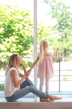 Sevimli küçük kız evde pencere yanında olan kadın