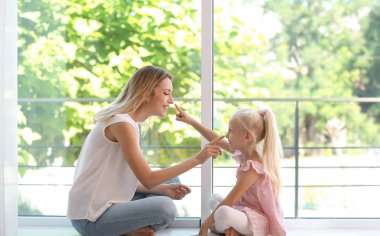Sevimli küçük kız evde pencere yanında olan kadın