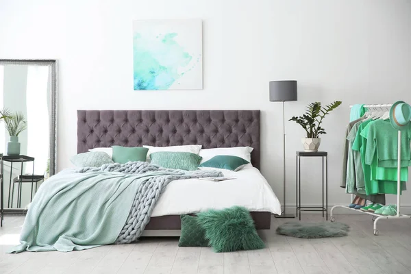 Stylish bedroom interior with clothes rack and mint decor elements